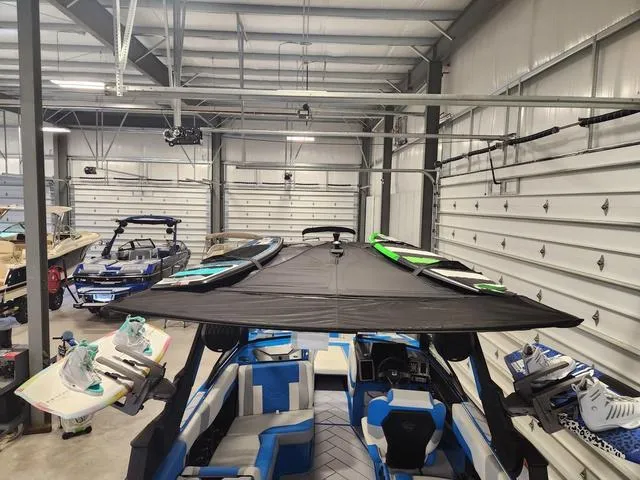 Slide: The Image of 2023 Malibu 26 LSV boat in storage facility with surfboards and wakeboards. - 21