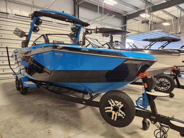 Slide: The Image of 2023 Malibu 26 LSV boat in blue and black on a trailer in a showroom. - 32