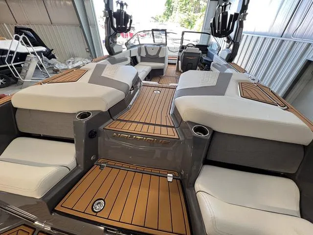 Slide: The Image of 2024 Nautique Super Air Nautique G23 interior with teak flooring and cushioned seating. - 13