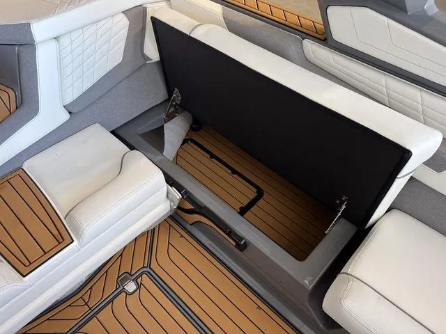 Slide: The Image of 2024 Nautique Super Air Nautique G23 interior storage compartment with white seating and teak flooring. - 19