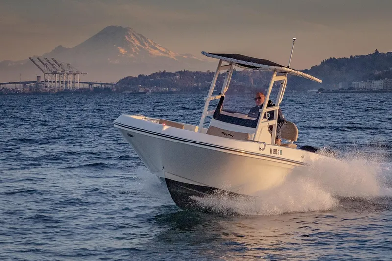 Slide: The Image of 2022 Bayliner Trophy T22CC boat cruising on water with scenic mountain backdrop. - 1
