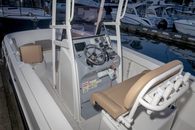 Slide: The Image of 2022 Bayliner Trophy T22CC boat interior with steering console and seating at marina. - 13