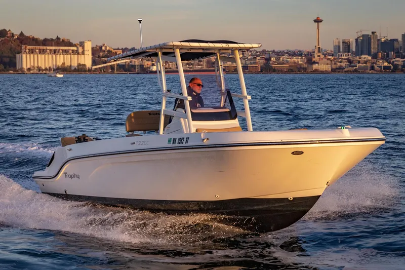 Slide: The Image of 2022 Bayliner Trophy T22CC boat cruising on water with city skyline in background. - 5