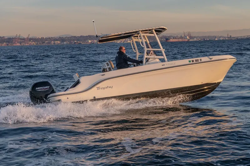 Slide: The Image of 2022 Bayliner Trophy T22CC boat cruising on open water at sunset. - 7