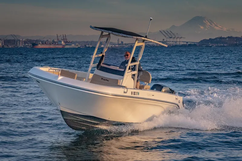 Slide: The Image of 2022 Bayliner Trophy T22CC boat cruising on open water with scenic mountain backdrop. - 8