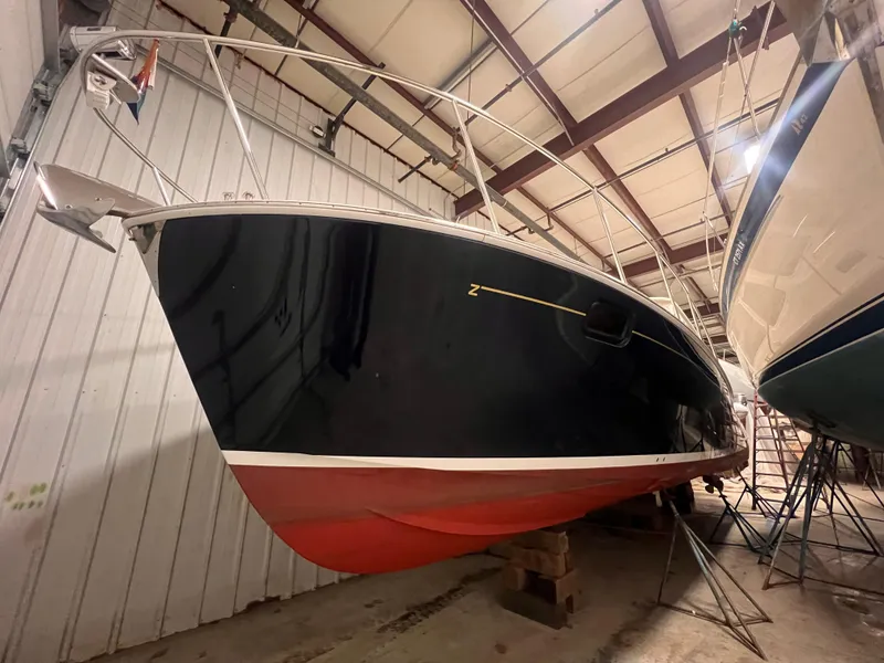 Slide: The Image of 2013 MJM 40z Downeast boat in indoor storage, showcasing sleek design and red hull. - 13