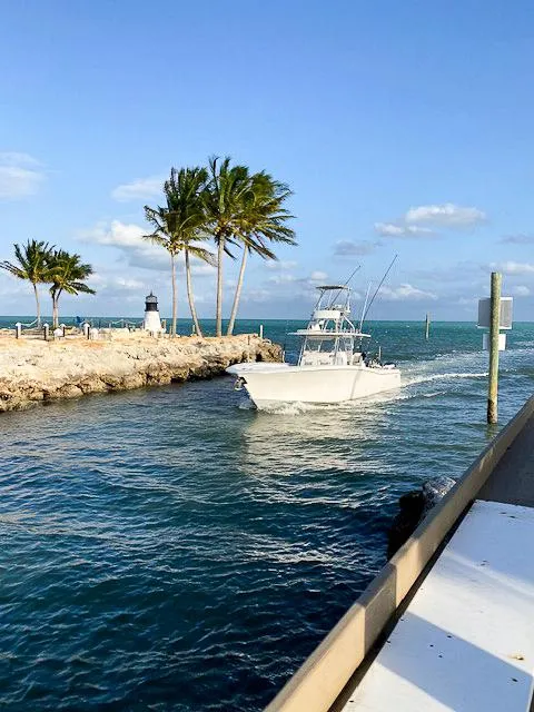Slide: The Image of 2020 Invincible 42 Open Fisherman boat cruising near palm trees and lighthouse. - 2