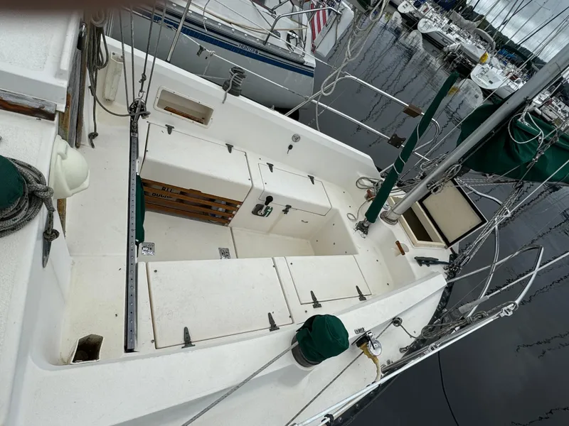 Slide: The Image of 1987 Nimble 30 sailboat cockpit with storage compartments, docked at a marina. - 2
