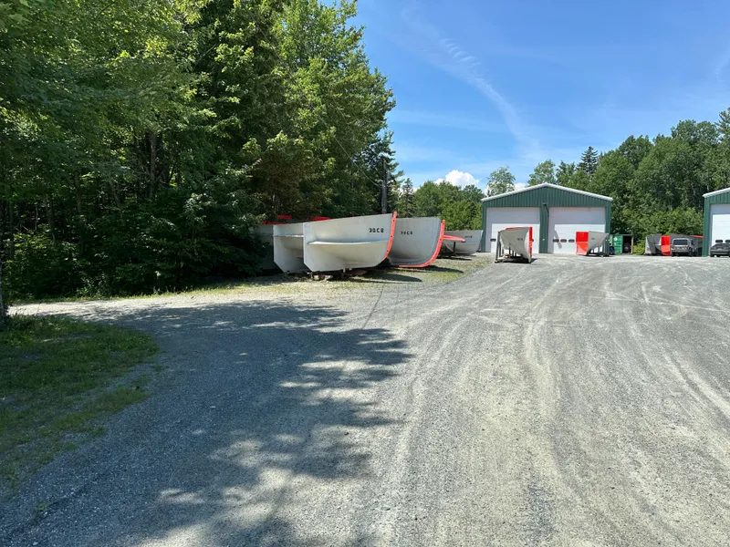 Slide: The Image of Outdoor storage area with Young Brothers 2020 hull molds and metal buildings under a clear sky. - 12