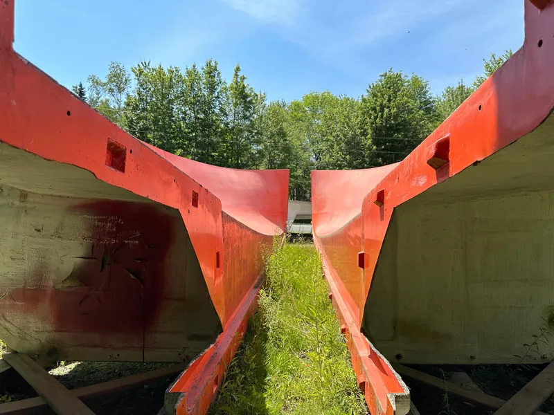 Slide: The Image of Red Young Brothers hull molds, 2020 model, set outdoors with green grass and trees. - 2