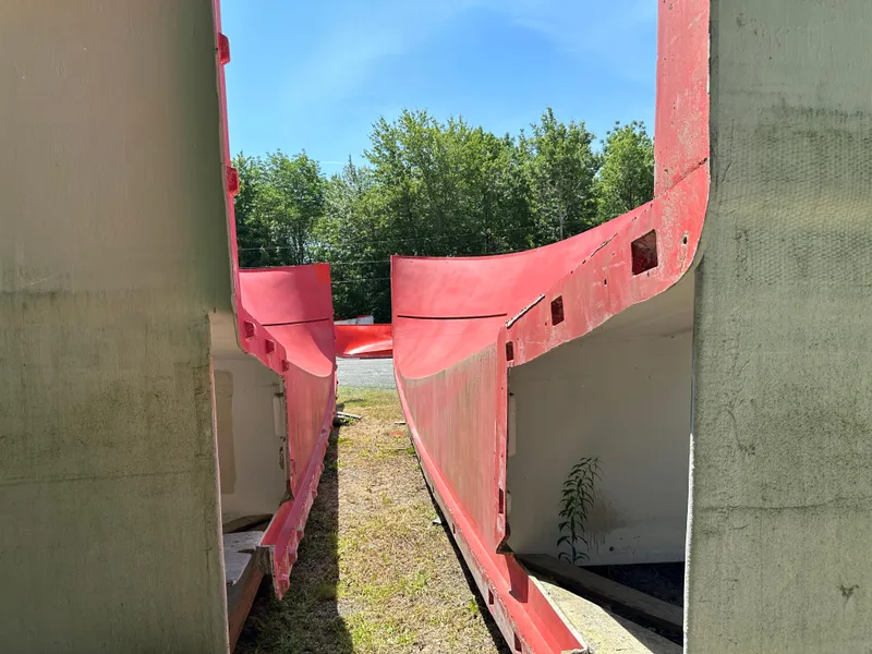 Slide: The Image of Red and beige boat hull molds by Young Brothers, 2020, outdoors with trees in background. - 6