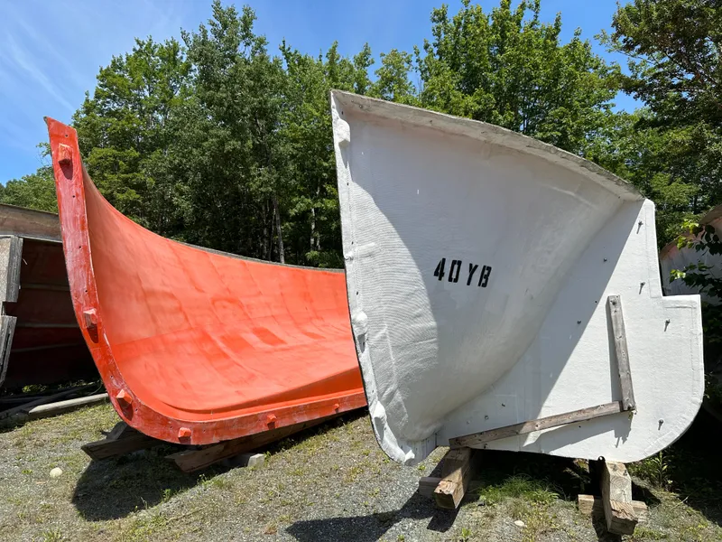 Slide: The Image of Two large boat hull molds, one red and one white, outdoors. - 8