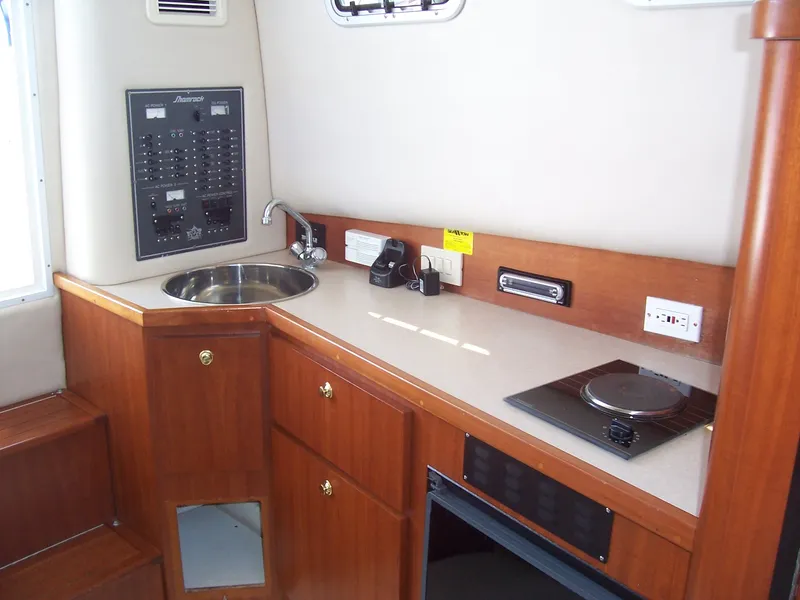 Slide: The Image of 1999 Shamrock 290 Walkaround boat interior kitchen with sink, stove, and control panel. - 2