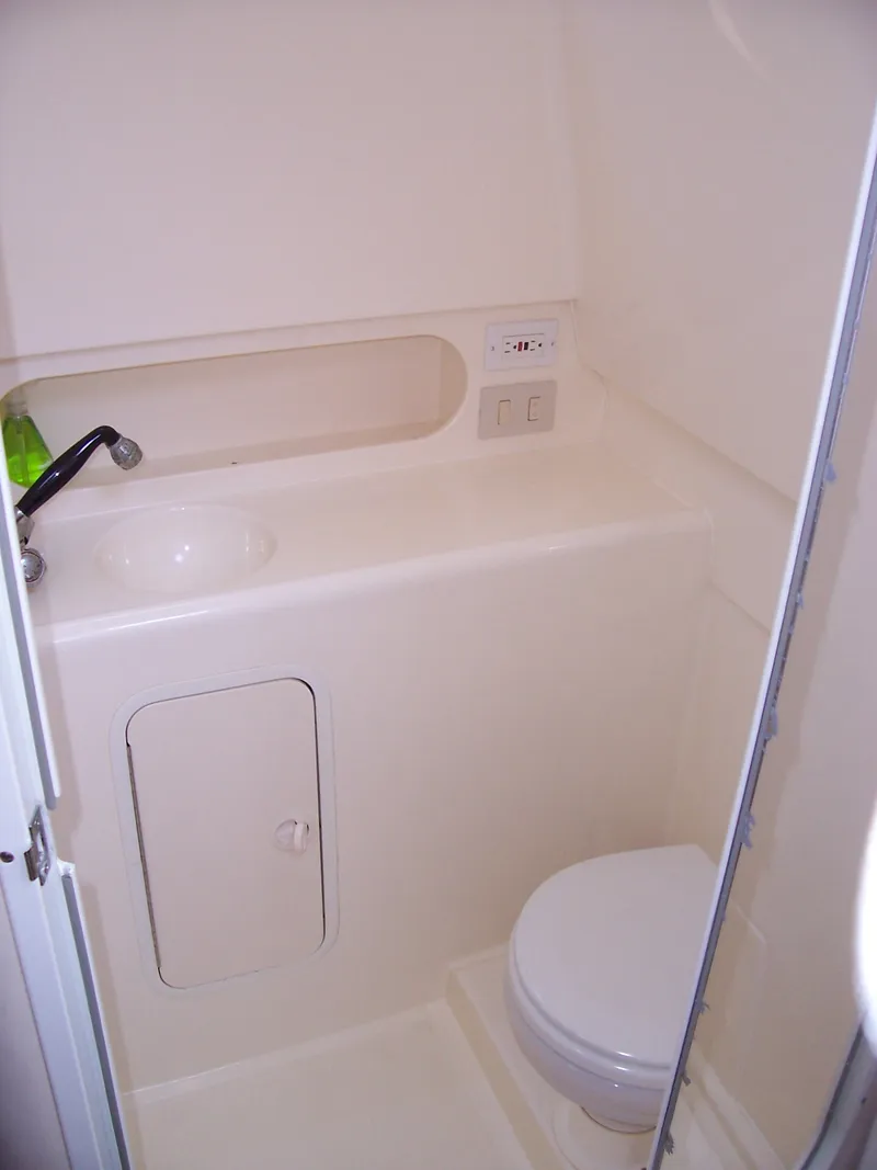 Slide: The Image of Compact bathroom in a 1999 Shamrock 290 Walkaround boat with sink and toilet. - 4