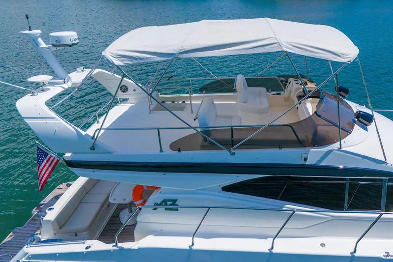 Slide: The Image of Azimut 43 Fly 1998 yacht with canopy, docked on calm water, featuring American flag. - 10