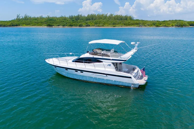 Slide: The Image of Azimut 43 Fly 1998 yacht cruising on clear blue water near a lush green shoreline. - 4