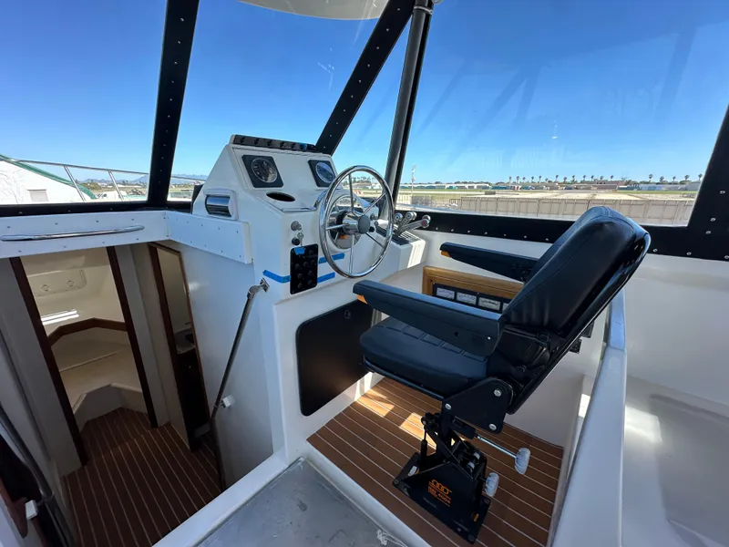 Slide: The Image of 1992 Custom Hueneme Boat Works helm station with captain's chair and steering wheel. - 23