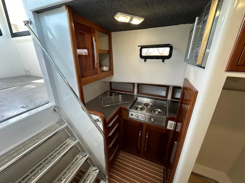 Slide: The Image of Compact kitchen area in a 1992 Custom Hueneme Boat Works vessel with wooden cabinets and stainless steel appliances. - 27