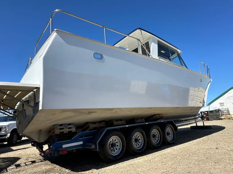 Slide: The Image of 1992 Custom Hueneme Boat Works on trailer, side view, clear sky background. - 7