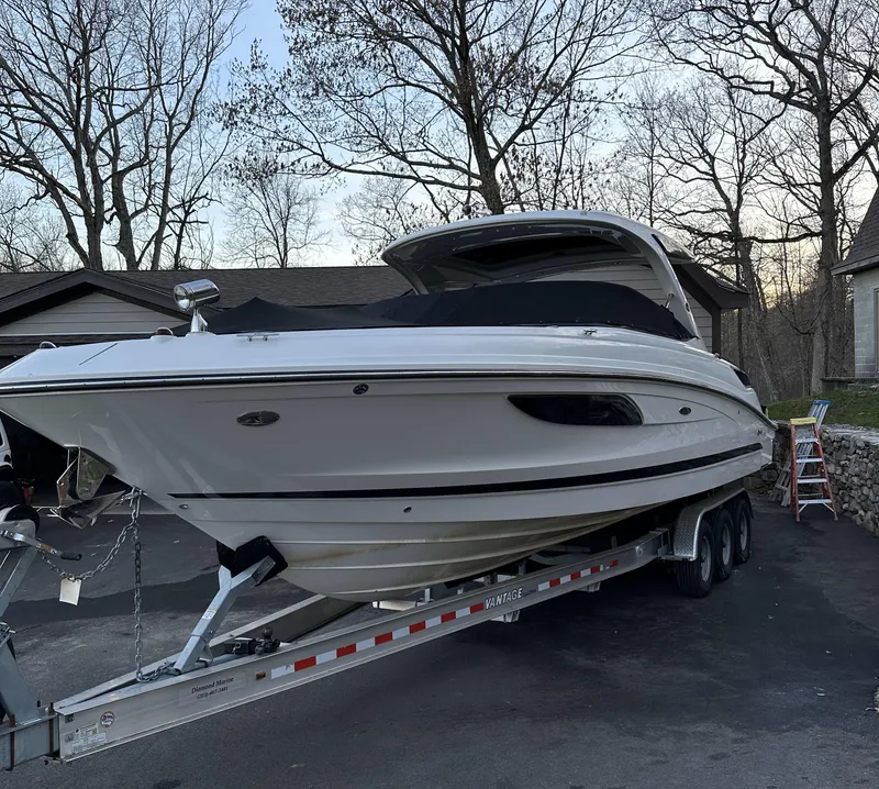 Slide: The Image of 2014 Sea Ray 350 SLX boat on trailer, parked in driveway, surrounded by trees. - 0