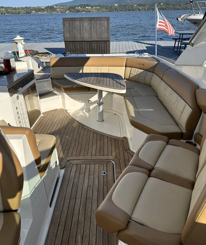 Slide: The Image of 2014 Sea Ray 350 SLX boat interior with tan seating and wooden deck, docked by a lake. - 11