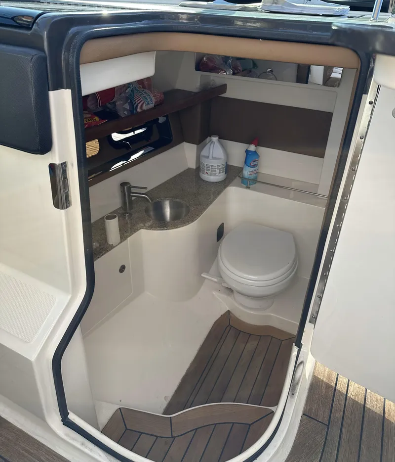 Slide: The Image of 2014 Sea Ray 350 SLX boat interior with compact bathroom, sink, and toilet. - 14