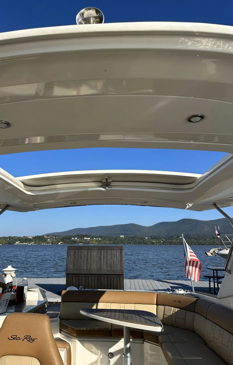 Slide: The Image of 2014 Sea Ray 350 SLX boat interior with open roof, lake view, and American flag. - 15