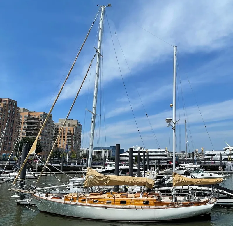 Slide: The Image of 1983 Cherubini 44 Ketch sailboat docked in a marina with cityscape background. - 1