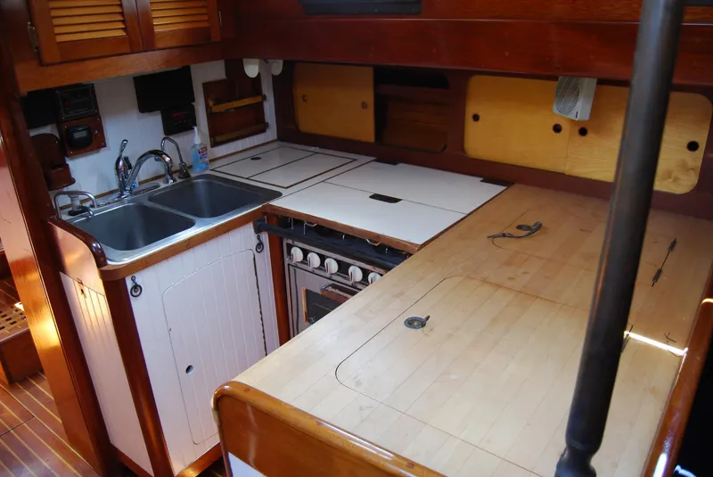 Slide: The Image of 1983 Cherubini 44 Ketch galley with sink, stove, and wooden cabinetry. - 4