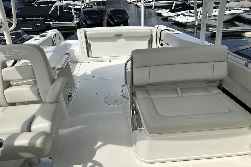 Slide: The Image of 2017 Boston Whaler 270 Vantage boat interior with white seating at marina. - 12