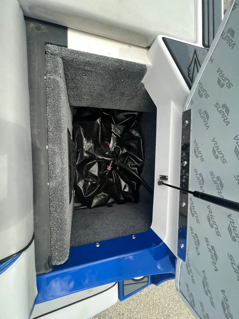 Slide: The Image of Storage compartment of a 2015 Supra SG 400 boat, featuring interior padding and a black bag. - 11
