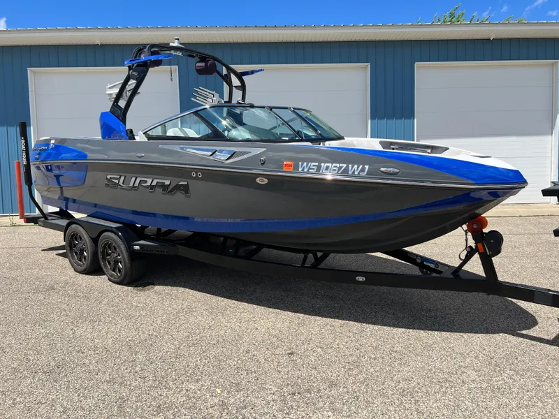 Slide: The Image of 2015 Supra SG 400 boat on trailer, blue and gray, parked outdoors. - 33