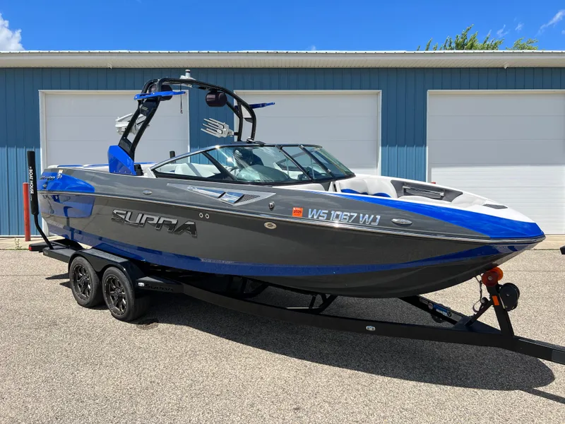 Slide: The Image of 2015 Supra SG 400 boat on trailer, parked outside blue garage. - 34