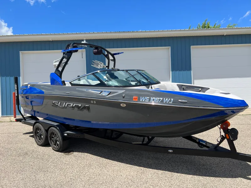 Slide: The Image of 2015 Supra SG 400 boat on trailer, blue and gray, parked outside a garage. - 35