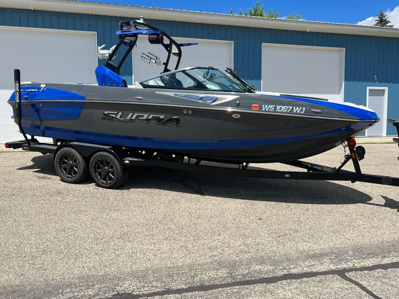 Slide: The Image of 2015 Supra SG 400 boat on trailer, parked outside blue building. - 4