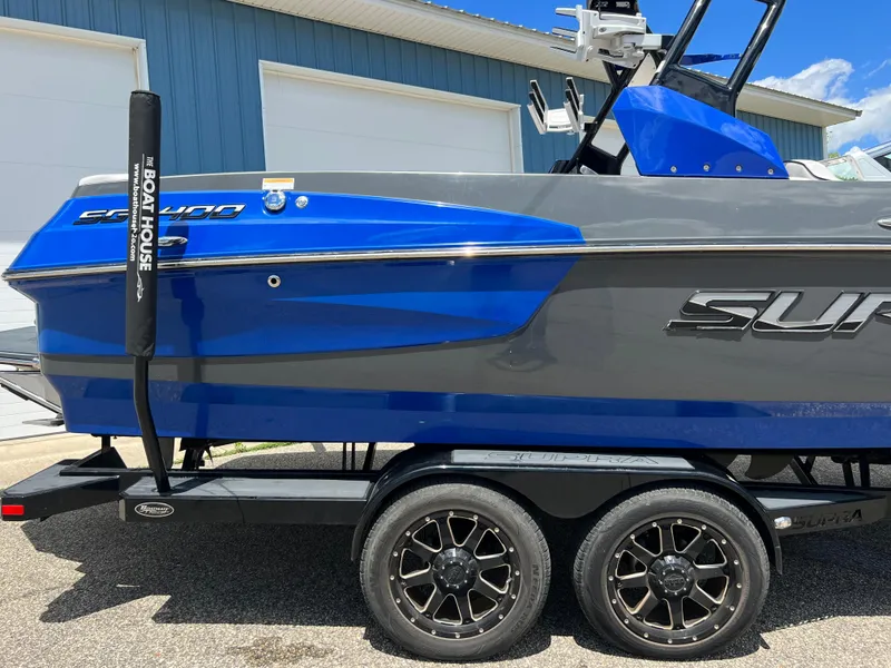Slide: The Image of 2015 Supra SG 400 boat on trailer, blue and gray design, parked outdoors. - 5