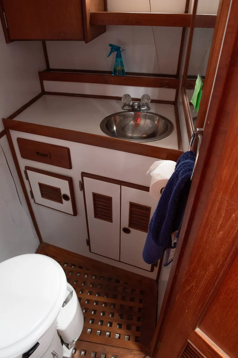 Slide: The Image of 1978 CHB Puget Trawler 37 bathroom with sink, toilet, and wooden cabinetry. - 14