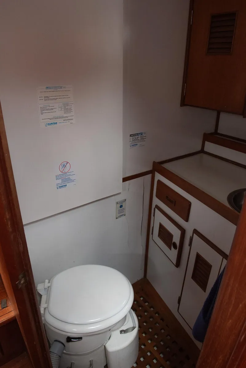 Slide: The Image of 1978 CHB Puget Trawler 37 bathroom with toilet, sink, and wooden cabinetry. - 15