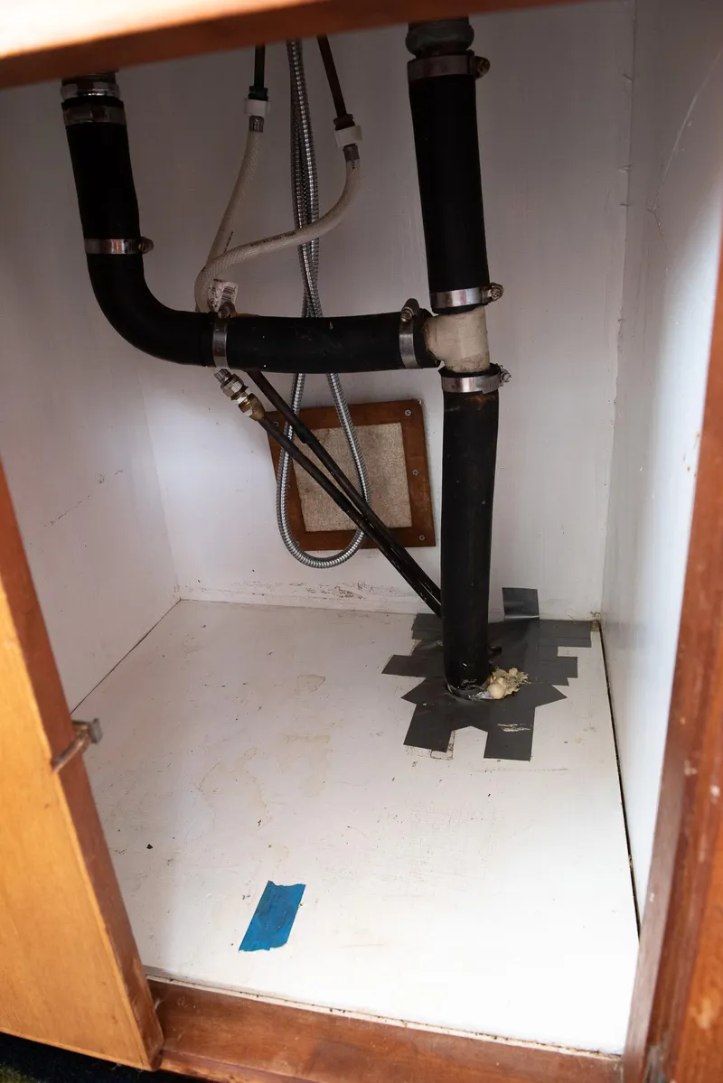 Slide: The Image of 1978 CHB Puget Trawler 37 plumbing system with black pipes and duct tape repair. - 21