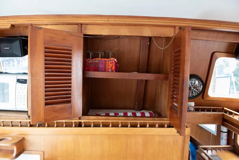 Slide: The Image of 1978 CHB Puget Trawler 37 interior with open wooden cabinet and nautical decor. - 22