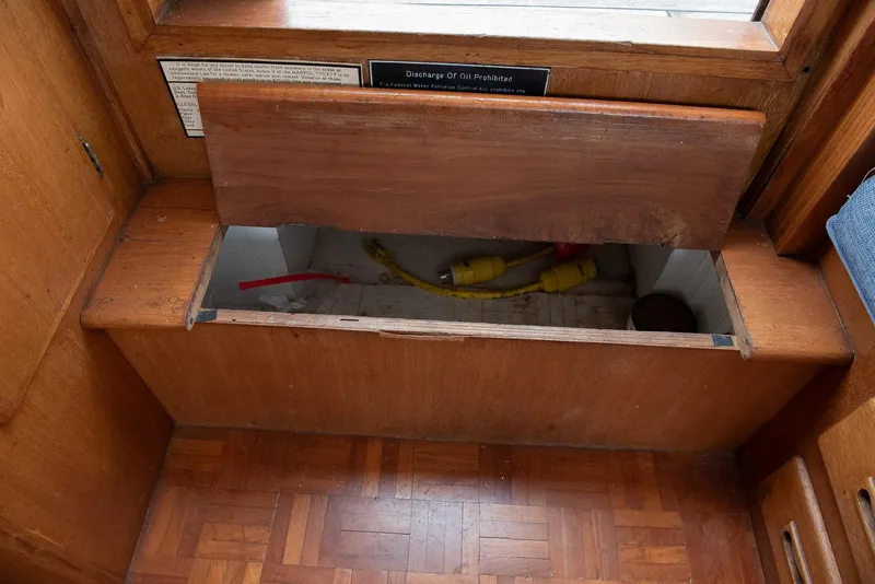 Slide: The Image of 1978 CHB Puget Trawler 37 interior storage compartment with wooden finish and visible cables. - 26