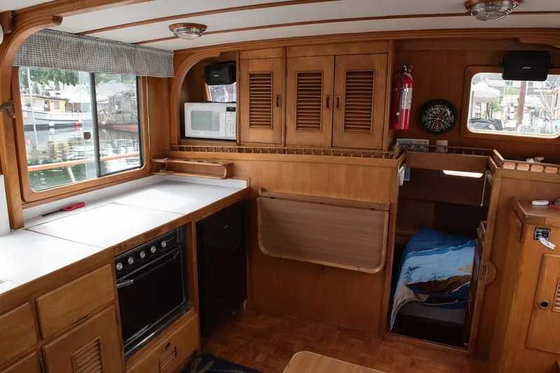 Slide: The Image of 1978 CHB Puget Trawler 37 interior with kitchen, bed, and wooden cabinetry. - 3