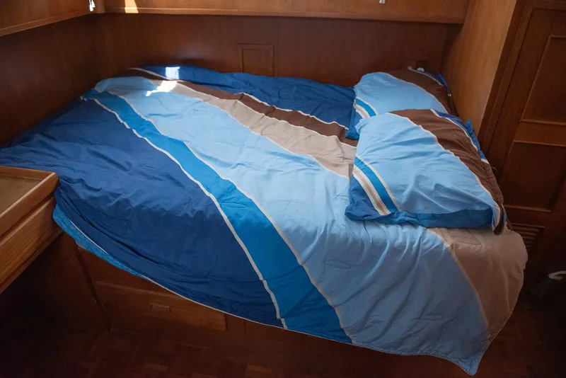 Slide: The Image of Cozy bed with blue and brown striped bedding in a 1978 CHB Puget Trawler 37 cabin. - 34