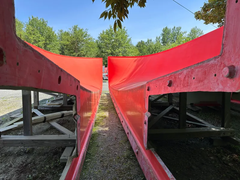Slide: The Image of 2024 Beal Calvin Beal MOLDS boat hulls, vibrant red, outdoors, surrounded by trees. - 11