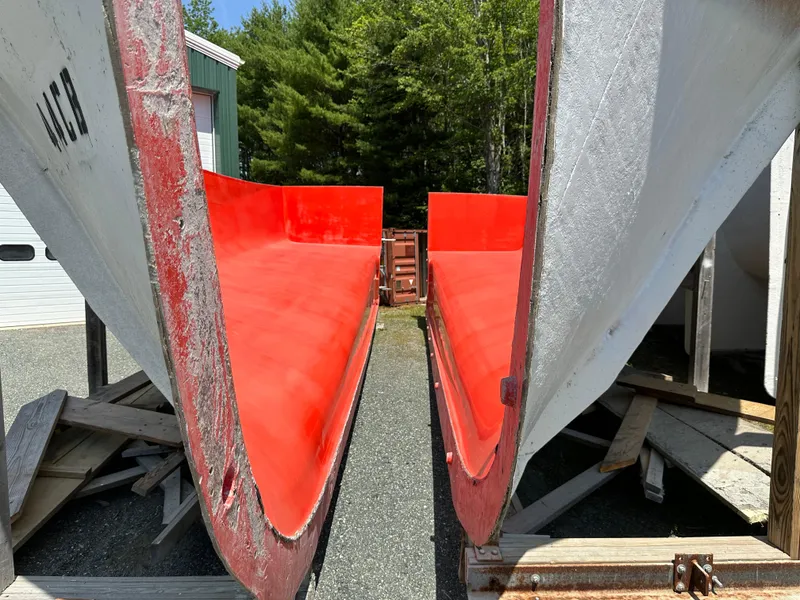 Slide: The Image of 2024 Beal Calvin Beal MOLDS boat hulls, red interior, outdoor setting with trees. - 2