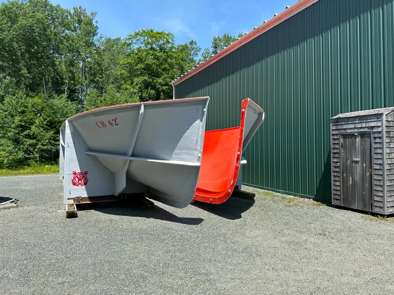Slide: The Image of 2024 Beal Calvin Beal MOLDS boat hulls outside a green building, surrounded by trees. - 5