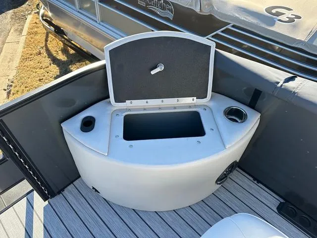 Slide: The Image of 2024 SunCatcher Fusion 322FC boat storage compartment with open lid and cup holders. - 16