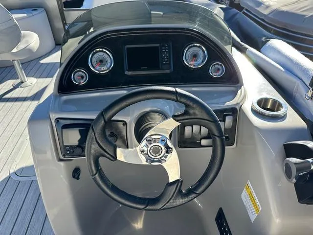 Slide: The Image of 2024 SunCatcher Fusion 322FC boat dashboard with steering wheel and gauges. - 9