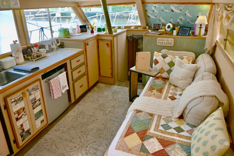 Slide: The Image of Cozy 1979 Uniflite Double Cabin interior with quilted sofa, kitchenette, and nautical decor. - 11