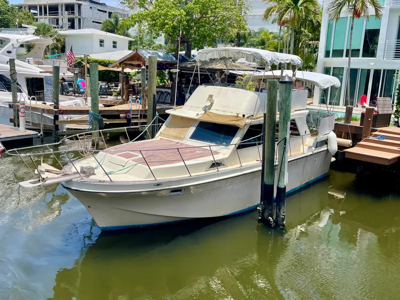 Slide: The Image of 1979 Uniflite Double Cabin boat docked in a marina, surrounded by lush greenery. - 2